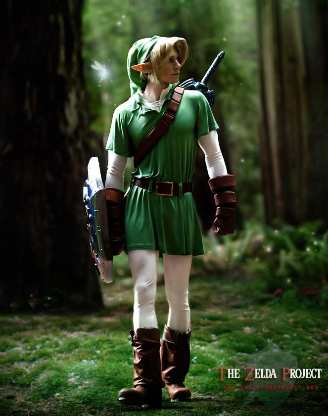 1boy belt blonde_hair boot cosplay forest full_body link male photo pointy_ears shield sword the_legend_of_zelda tunic wings