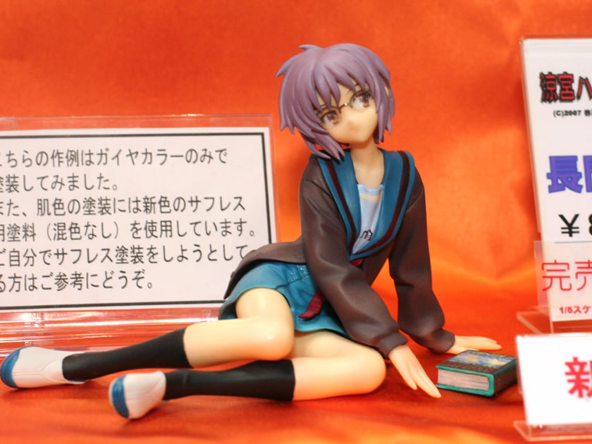 1girl arm_support book figure glasses lying nagato_yuki on_side photo purple_hair school_uniform serafuku short_hair sitting solo suzumiya_haruhi_no_yuuutsu wonder_festival wonder_festival_2007