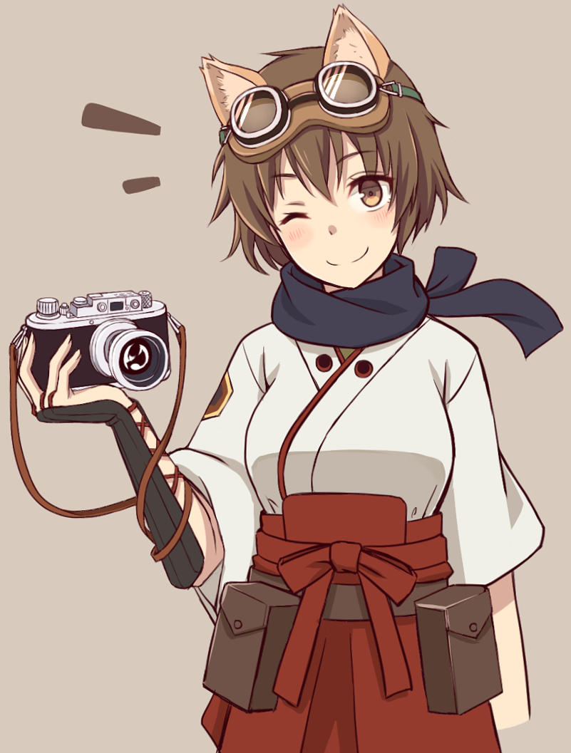 1girl animal_ears blush brown_eyes brown_hair camera fox_ears goggles goggles_on_head japanese_clothes katou_keiko looking_at_viewer momiji7728 one_eye_closed scarf short_hair simple_background smile solo tan_background world_witches_series