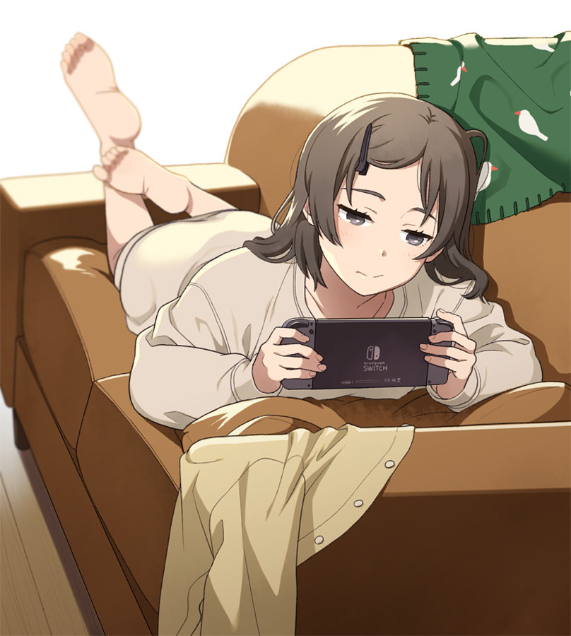 1girl barefoot blurry brown_eyes brown_hair couch depth_of_field hair_ornament hairclip long_hair lying mattaku_mousuke nintendo_switch on_stomach original playing_games solo white_background