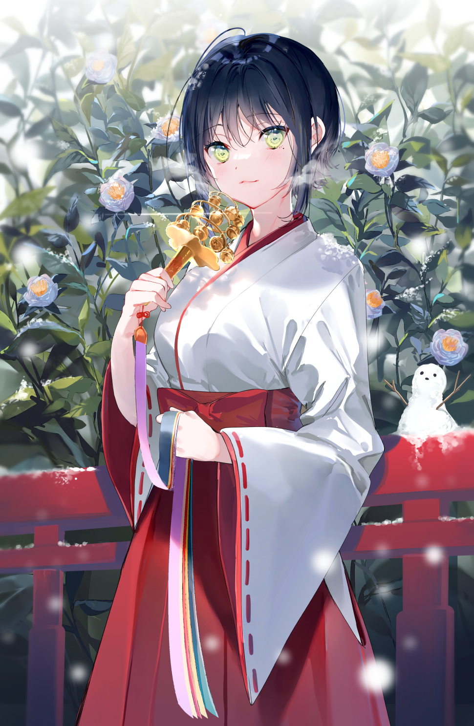 1girl bangs bell black_hair blush bush closed_mouth cowboy_shot eyebrows_visible_through_hair flower green_eyes hakama highres hip_vent holding japanese_clothes jingle_bell kimono long_sleeves looking_at_viewer miko miwano_ragu mole mole_under_eye motion_blur official_art original railing red_flower red_hakama smile snow snow_sculpture snowing solo white_kimono wide_sleeves