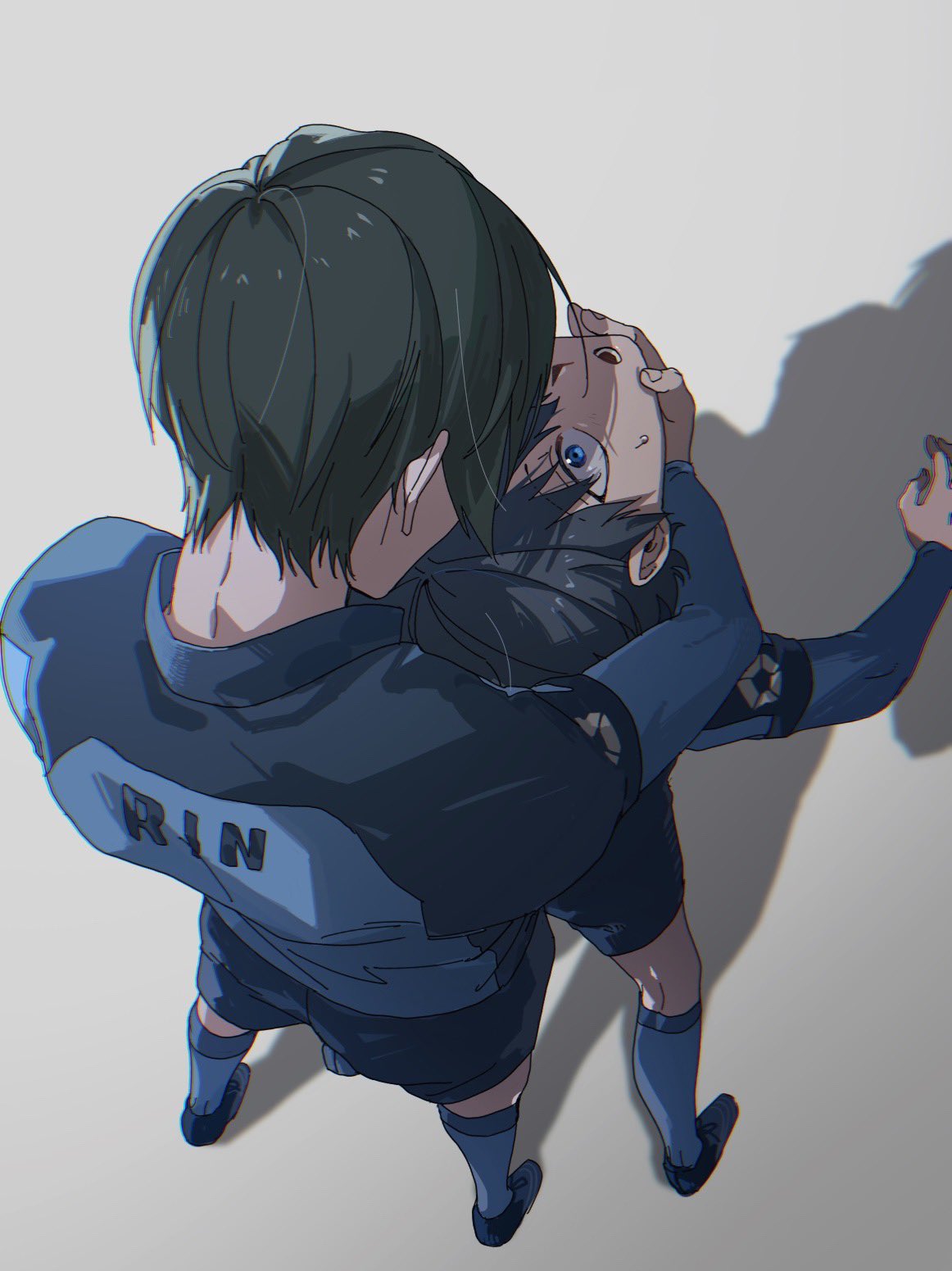2boys bangs black_footwear black_hair blue_eyes blue_lock blue_shirt blue_shorts blue_socks blue_tkse character_name chromatic_aberration from_above full_body grabbing grabbing_from_behind grey_background hand_on_another's_chin highres isagi_yoichi itoshi_rin long_sleeves looking_at_another male_focus multiple_boys open_mouth shadow shirt shoes short_hair shorts simple_background soccer_uniform socks sportswear standing