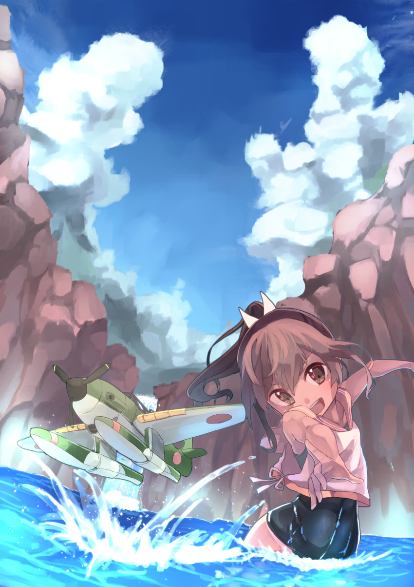 1girl action airplane brown_eyes brown_hair cliff clouds commentary crop_top fisheye head_tilt highres i-401_(kantai_collection) kantai_collection one-piece_swimsuit open_mouth partially_submerged ponytail sailor_collar saraki school_swimsuit seaplane short_hair sky smile solo splashing swimsuit swimsuit_under_clothes throwing water waterfall