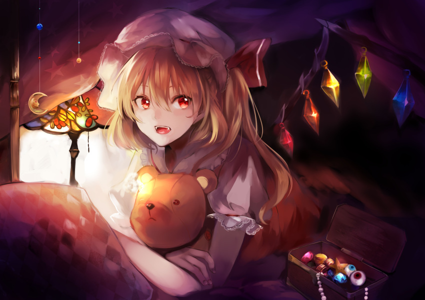 1girl absurdres blonde_hair fangs flandre_scarlet hair_between_eyes hat hat_ribbon highres holding jewelry lace-trimmed_sleeves lace_trim lamp long_hair looking_at_viewer lying mob_cap on_stomach open_mouth pillow puffy_short_sleeves puffy_sleeves red_eyes ribbon short_sleeves side_ponytail smile solo stuffed_animal stuffed_toy teddy_bear touhou upper_body wings yuki_shiro_(ubq315)