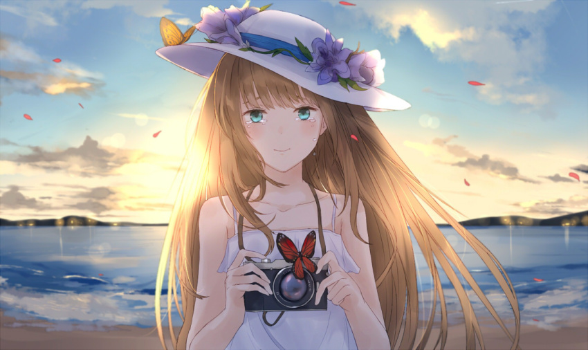 1girl bare_shoulders beach blonde_hair blue_eyes blue_sky butterfly camera clouds commentary hat kachiino long_hair looking_at_viewer mountain original petals sky sleeveless smile solo tears