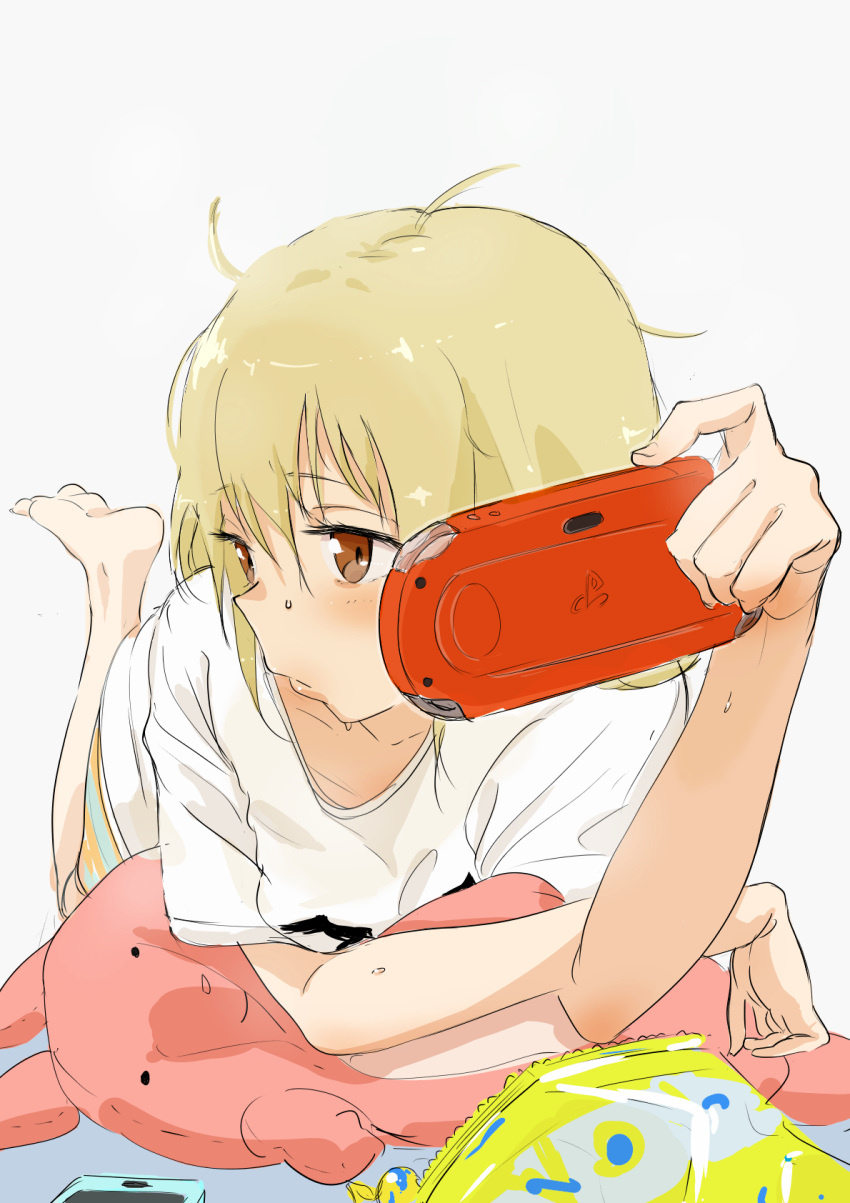 1girl bag_of_chips bangs barefoot blonde_hair blush bouen brown_eyes cellphone closed_mouth eyebrows_visible_through_hair feet_up futaba_anzu grey_background hair_between_eyes handheld_game_console highres idolmaster idolmaster_cinderella_girls lips long_hair looking_to_the_side lying messy_hair on_stomach phone playstation_portable revision shirt short_sleeves simple_background smartphone solo stuffed_animal stuffed_bunny stuffed_toy t-shirt