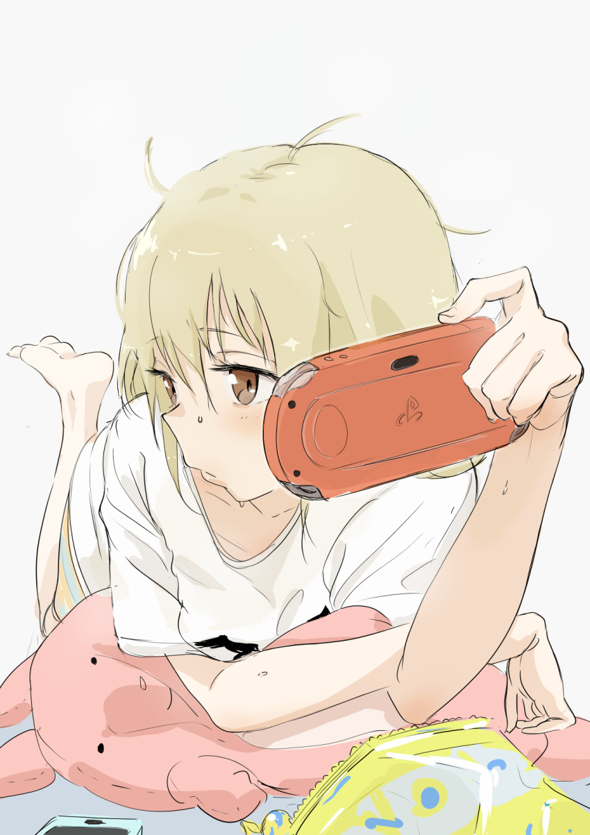 1girl bag_of_chips bangs barefoot blonde_hair blush bouen brown_eyes cellphone closed_mouth eyebrows_visible_through_hair feet_up futaba_anzu grey_background hair_between_eyes handheld_game_console highres idolmaster idolmaster_cinderella_girls lips long_hair looking_to_the_side lying messy_hair on_stomach phone playstation_portable shirt short_sleeves simple_background smartphone solo stuffed_animal stuffed_bunny stuffed_toy t-shirt