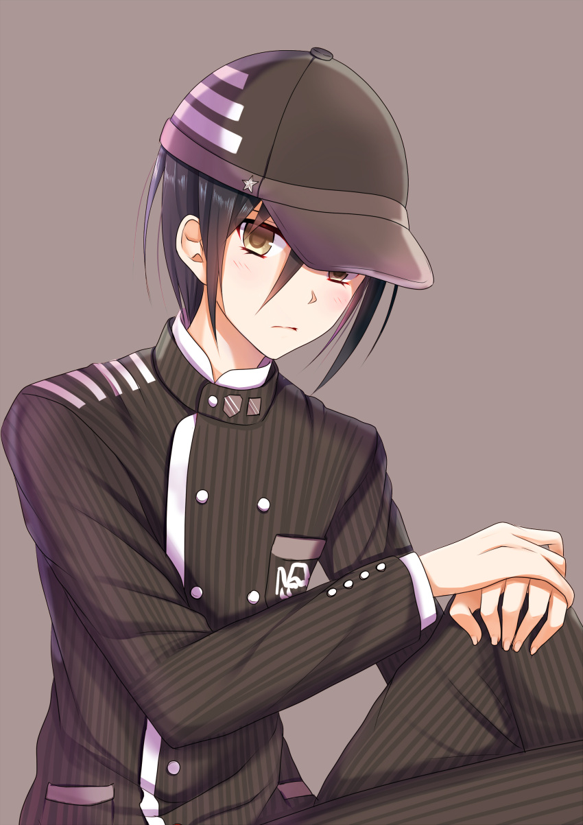 1boy absurdres akausagi baseball_cap black_hair black_pants blush brown_background brown_eyes brown_hat dangan_ronpa emblem gakuran hair_between_eyes hands_on_own_knee hat highres knee_up long_sleeves looking_at_viewer male_focus new_dangan_ronpa_v3 own_hands_together pants saihara_shuuichi school_uniform simple_background sitting solo striped vertical-striped_pants vertical_stripes