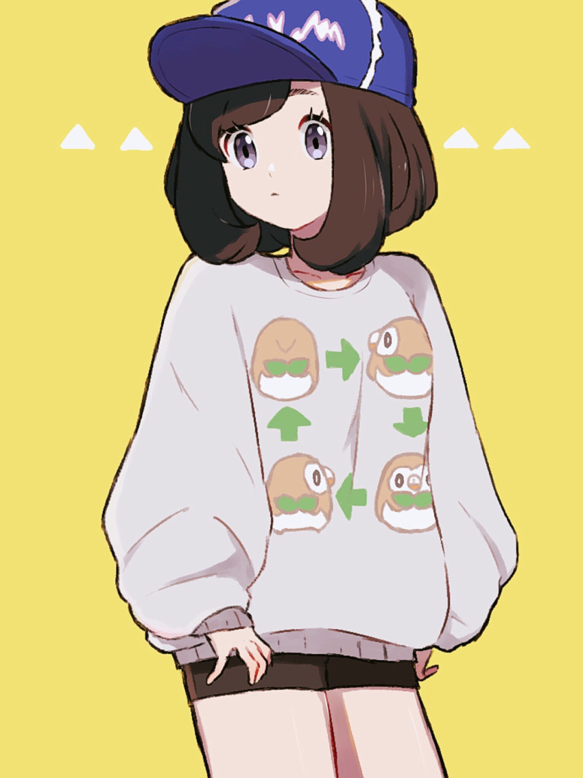 1girl alternate_costume baseball_cap black_hair black_shorts blue_hat gen_7_pokemon hat highres kn_9620 long_sleeves mizuki_(pokemon_sm) pokemon pokemon_(game) pokemon_sm rowlet short_hair shorts simple_background solo sweater yellow_background