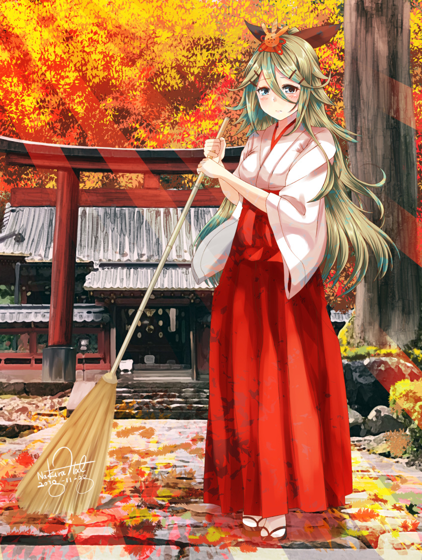 1girl autumn_leaves bangs blue_eyes blush breasts broom full_body green_hair hair_between_eyes hair_ornament hair_ribbon hairclip hakama highres holding holding_broom japanese_clothes kantai_collection leaf long_hair long_sleeves looking_at_viewer maple_leaf miko nakura_haru outdoors ponytail red_hakama ribbon sandals shrine sidelocks signature socks solo sunset sweeping white_footwear wide_sleeves yamakaze_(kantai_collection)