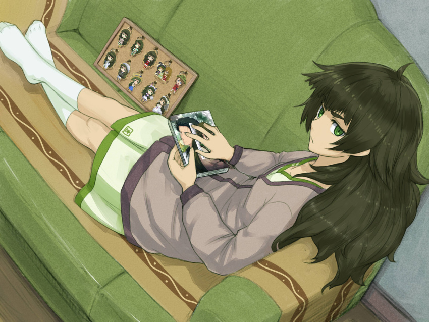 1girl black_hair book breasts couch dutch_angle green_eyes highres hiyajou_maho jacket keychain kiryuu_moeka long_hair long_sleeves looking_at_viewer manga_(object) menomorute okabe_rintarou shirt sitting small_breasts socks solo steins;gate steins;gate_0 tennouji_nae thick_eyebrows white_footwear