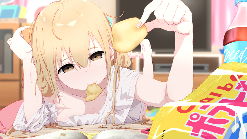 1girl absurdres barefoot blonde_hair blurry blurry_background bouen brown_eyes chips cola commentary depth_of_field food futaba_anzu highres holding idolmaster idolmaster_cinderella_girls looking_at_viewer loose_clothes loose_shirt lying mouth_hold on_stomach potato_chips shirt soda_bottle solo