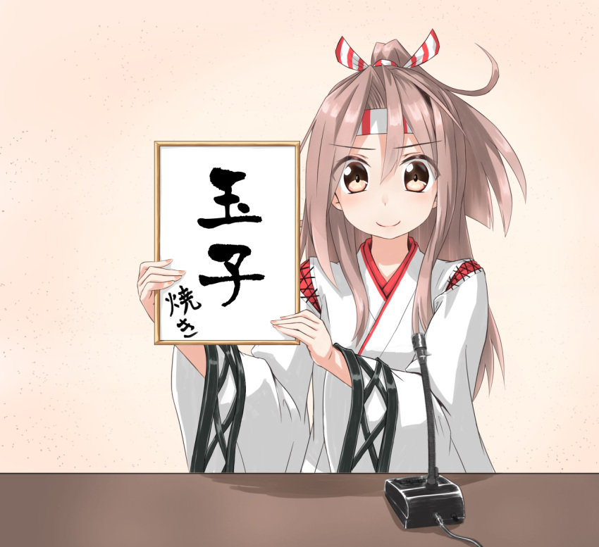 1girl brown_eyes brown_hair commentary_request gradient gradient_background hachimaki headband high_ponytail highres holding holding_sign kantai_collection koda light_brown_hair long_hair looking_at_viewer microphone parody pink_background ponytail reiwa sign smile smug solo table translated zuihou_(kantai_collection)