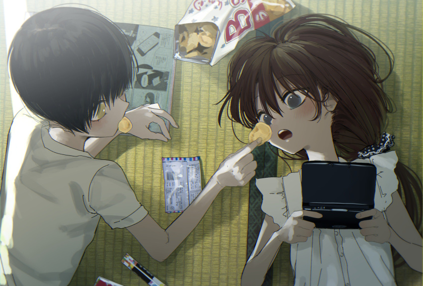 1boy 1girl absurdres bag black_hair blue_eyes blue_ribbon blush brown_hair chips commentary feeding food food_in_mouth handheld_game_console highres holding_handheld_game_console honryou_wa_naru long_hair looking_at_another lying manga_(object) nintendo_3ds on_floor open_mouth original potato_chips ribbon round_teeth shirt short_sleeves sunlight tatami teeth tied_hair upper_body white_shirt yellow_eyes
