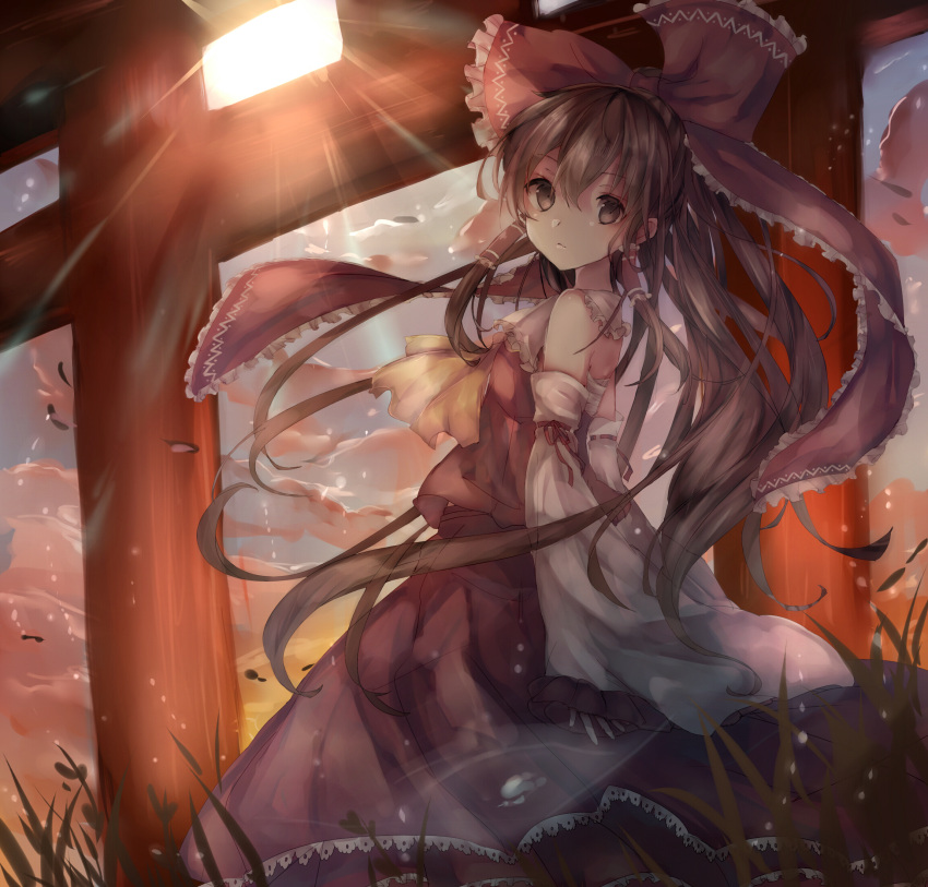 1girl ascot bow brown_eyes brown_hair day detached_sleeves hair_bow hair_tubes hakurei_reimu highres inaresi leaning_back light_rays long_hair looking_at_viewer nontraditional_miko outdoors red_bow red_skirt ribbon-trimmed_sleeves ribbon_trim shirt skirt skirt_set sleeveless sleeveless_shirt solo sunbeam sunlight torii touhou wide_sleeves wind