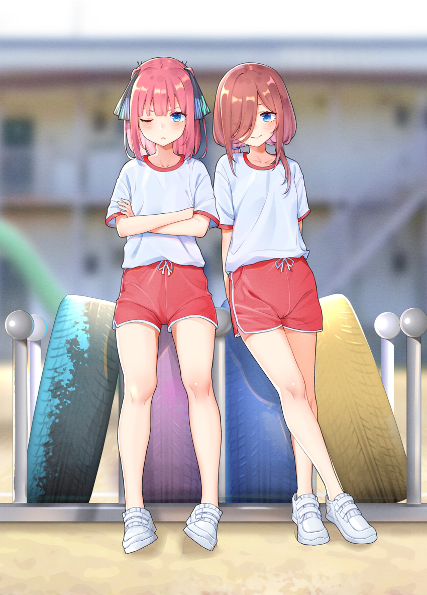 2girls ;( arms_behind_back blue_eyes blurry blurry_background blush closed_mouth commentary_request crossed_arms crossed_legs full_body go-toubun_no_hanayome gym_uniform hair_over_one_eye hair_ribbon highres kongbai looking_at_viewer medium_hair multiple_girls nakano_miku nakano_nino outdoors pink_hair red_shorts ribbon shirt short_sleeves shorts siblings sisters smile standing t-shirt tire v-shaped_eyebrows white_footwear white_shirt