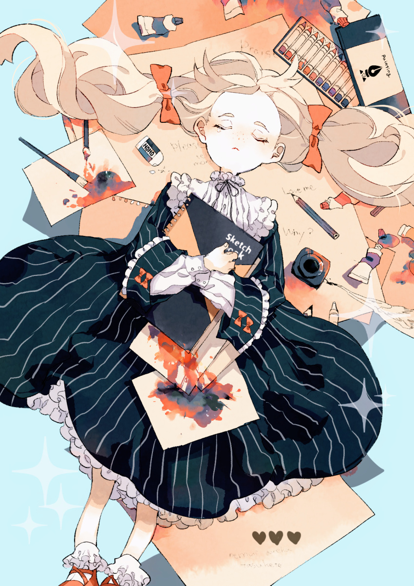 1girl black_dress blonde_hair blue_background book bow closed_eyes dress eraser freckles frills hair_bow heart higashino highres holding holding_book inkwell long_sleeves lying on_back orange_bow original paint paint_tube paintbrush paper pencil quill red_footwear sketchbook socks solo sparkle tearing_up translation_request twintails white_legwear