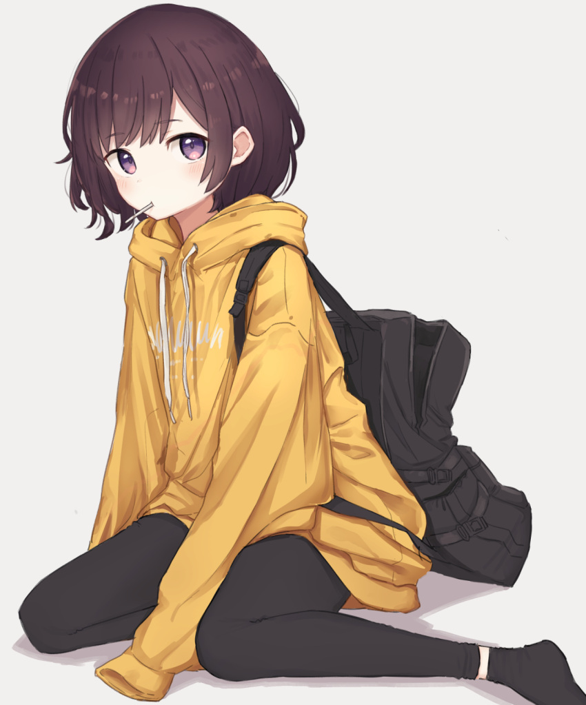 1girl backpack bag bangs black_legwear blush brown_hair candy clothes_writing commentary_request drawstring eyebrows_visible_through_hair food food_in_mouth highres hood hood_down leggings lollipop long_sleeves looking_at_viewer mouth_hold original short_hair sitting sleeves_past_fingers sleeves_past_wrists socks violet_eyes yellow_hoodie zuima