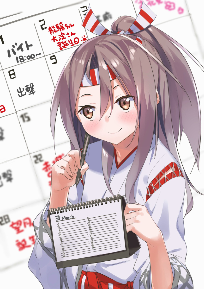 1girl calendar_(object) commentary_request gedoo_(gedo) hachimaki hakama hakama_pants headband high_ponytail highres japanese_clothes kantai_collection light_brown_hair long_hair pen ponytail red_hakama smile solo translation_request zuihou_(kantai_collection)