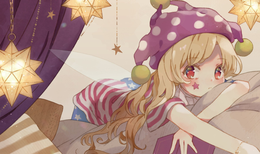 1girl american_flag_dress american_flag_legwear blonde_hair bracelet clownpiece curtains expressionless facial_mark fairy_wings hat highres indoors jester_cap jewelry looking_at_viewer lying nig_18 on_stomach pantyhose pillow polka_dot purple_headwear red_eyes short_sleeves solo star star_print touhou transparent_wings wings
