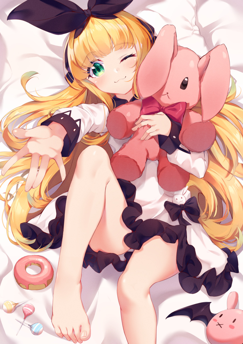 1girl ;3 bangs bare_legs barefoot bed_sheet black_bow black_ribbon blonde_hair blush bow bowtie candy closed_mouth commentary doughnut dress eyebrows_visible_through_hair food frilled_dress frills green_eyes hair_ribbon highres knee_up lollipop long_hair long_sleeves lying mononobe_alice nahaki nijisanji object_hug on_back one_eye_closed outstretched_arm red_neckwear ribbon solo stuffed_animal stuffed_bunny stuffed_toy very_long_hair virtual_youtuber white_dress