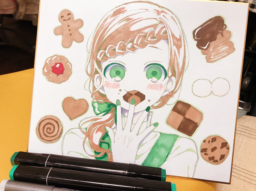 1girl blush bow braid brown_hair checkerboard_cookie chocolate_chip_cookie commentary_request cookie eating food food_on_face gingerbread_man green_bow green_eyes green_nails hair_bow highres long_hair looking_at_viewer nail_polish original photo shirt sofra solo thumbprint_cookie traditional_media upper_body white_shirt