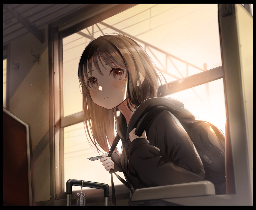 1girl backpack bag black_border black_hoodie border brown_eyes brown_hair chair commentary_request expressionless eyebrows_visible_through_hair highres holding hood hood_down light_blush long_sleeves looking_at_viewer medium_hair omamori original power_lines rolling_suitcase sitting sleeves_past_wrists solo ticket train_interior twilight upper_body utaka_(anyoanyot) window