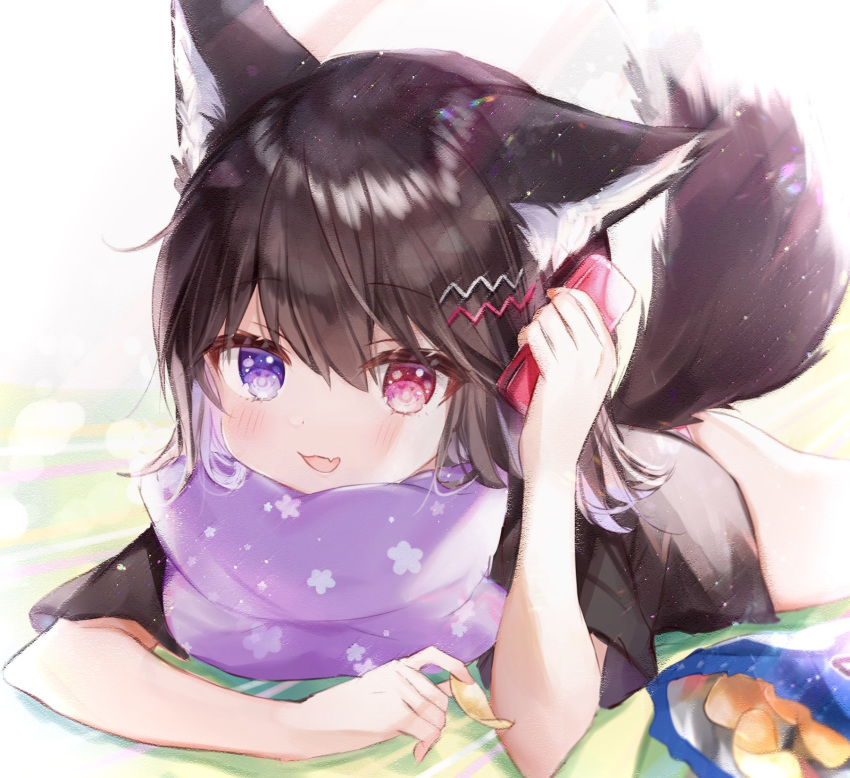 1girl :d animal_ears bag_of_chips black_shirt blue_eyes brown_hair cellphone chips commentary_request fang food heterochromia highres holding holding_phone lying medium_hair naked_shirt on_stomach open_mouth original phone pillow red_eyes rukako shirt short_sleeves skin_fang smartphone smile tail wolf_ears wolf_tail yoyogi_(rukako)