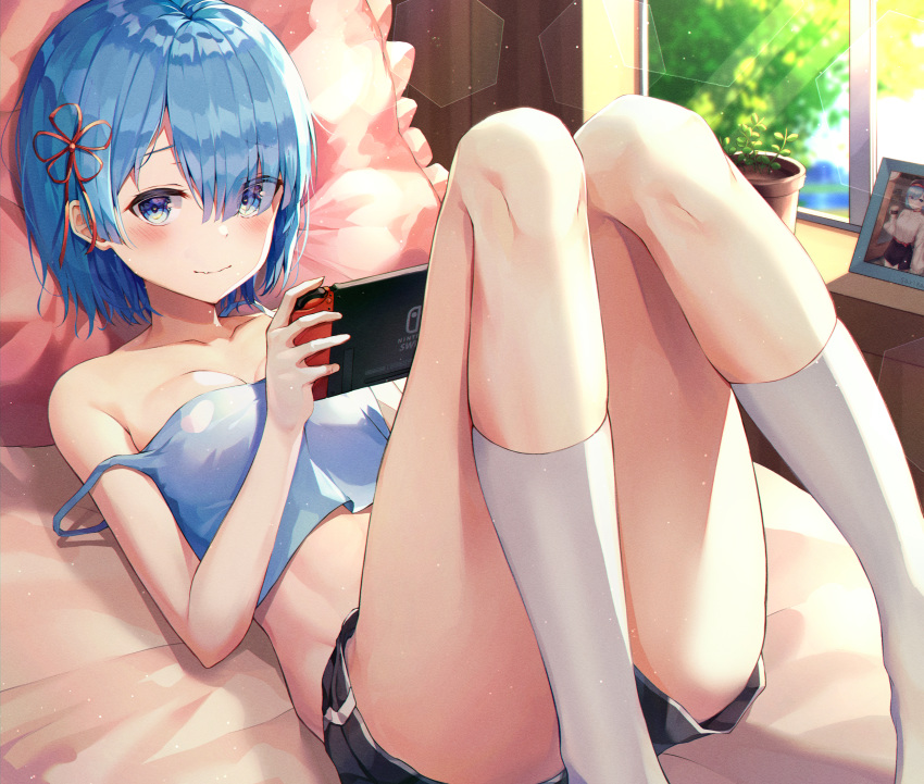 1girl absurdres bangs bare_shoulders bed black_shorts blue_eyes blue_hair blush breasts collarbone commentary crop_top day feet_out_of_frame frilled_pillow frills gyungsin hair_ornament hair_over_one_eye handheld_game_console highres huge_filesize indoors kneehighs knees_up looking_at_viewer lying medium_breasts midriff nintendo_switch on_back on_bed photo_(object) pillow plant playing_games potted_plant re:zero_kara_hajimeru_isekai_seikatsu rem_(re:zero) ribbon short_hair short_shorts shorts smile solo strap_slip thighs white_legwear window x_hair_ornament