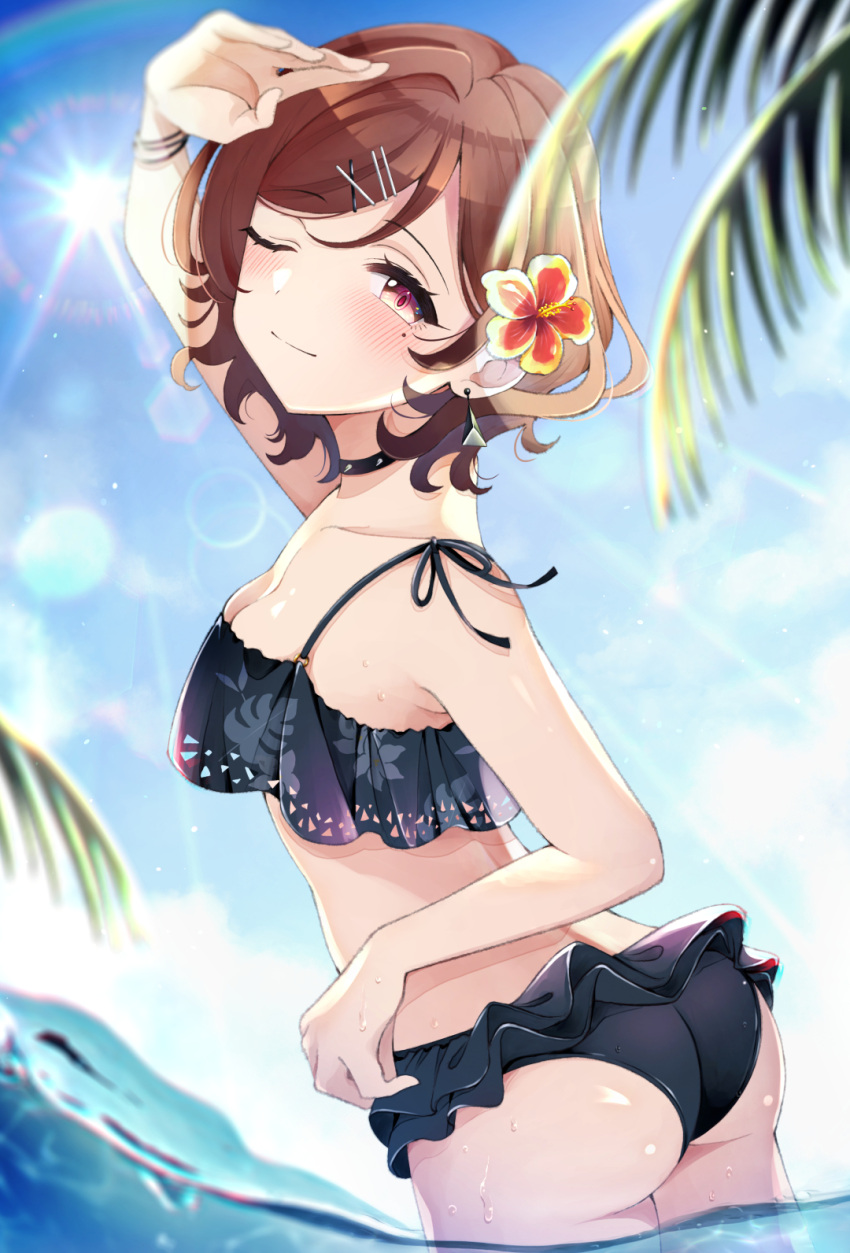 1girl ass bangs bikini black_bikini black_choker blue_sky blurry_foreground blush brown_hair choker closed_mouth commentary_request droplet earrings eyebrows_visible_through_hair flower from_behind hair_flower hair_ornament hairclip half-closed_eye hibiscus highres higuchi_madoka idolmaster idolmaster_shiny_colors jewelry leaf_print lens_flare looking_at_viewer looking_back mole mole_under_eye one_eye_closed palm_tree print_bikini shading_eyes short_hair sky smile solo spiked_choker spikes standing swept_bangs swimsuit tree umeume_(totoya) violet_eyes wading water wet