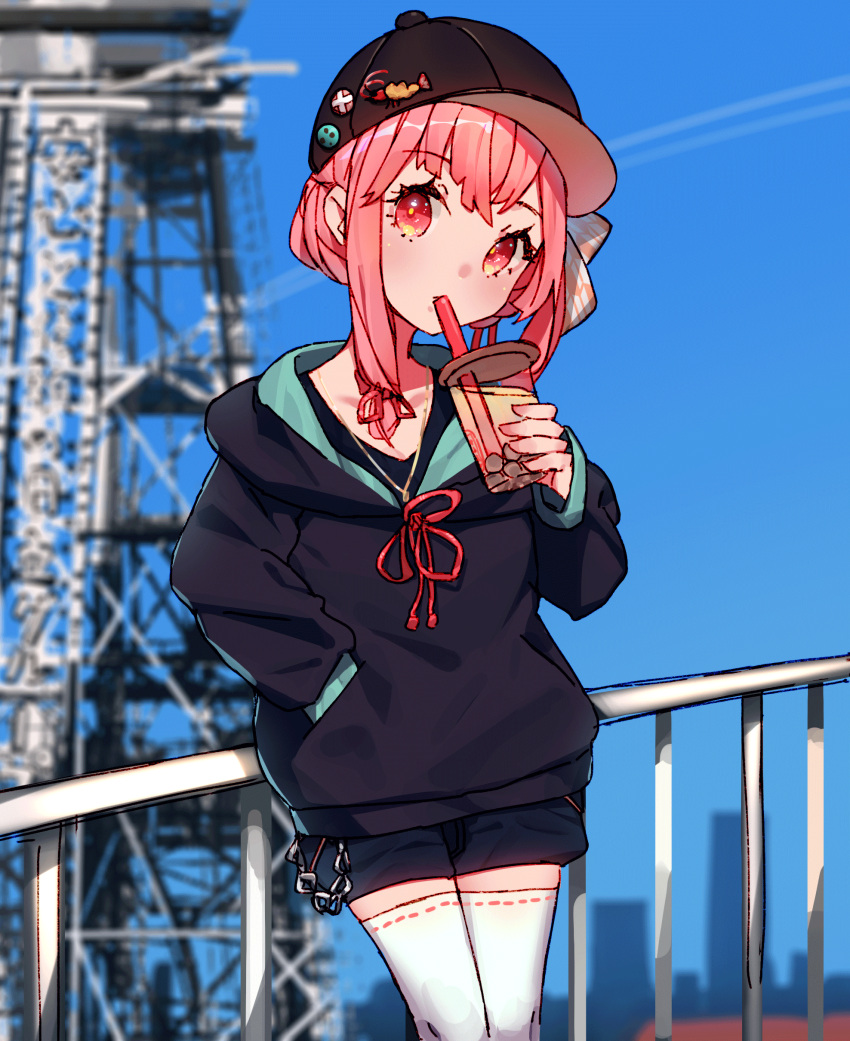 1girl absurdres badge baseball_cap black_headwear black_hoodie blurry blurry_background bubble_tea cio_hakatano cityscape commentary_request cowboy_shot cup drinking drinking_straw hair_tie handrail hat highres holding holding_cup hood hoodie kotonoha_akane leaning_back medium_hair pink_eyes pink_hair shorts thigh-highs tower voiceroid white_legwear