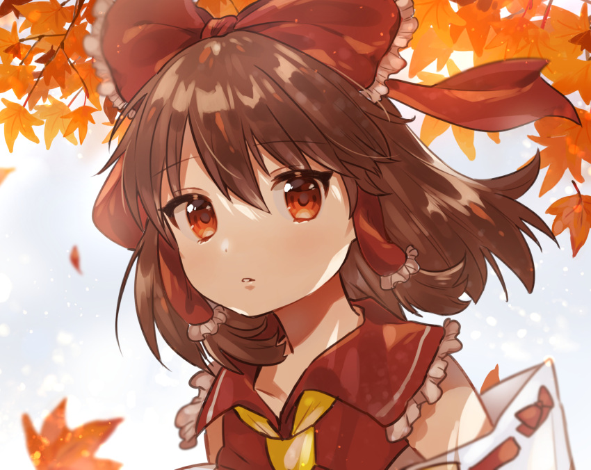 1girl autumn autumn_leaves blue_sky blurry blurry_background bow brown_hair commentary cravat day detached_sleeves eyebrows_visible_through_hair hair_between_eyes hair_blowing hair_bow hair_tubes hakurei_reimu highres leaf light_particles looking_at_viewer maple_leaf outdoors parted_lips red_eyes red_vest ribbon-trimmed_sleeves ribbon_trim short_hair sky solo standing suicchonsuisui touhou upper_body vest yellow_neckwear