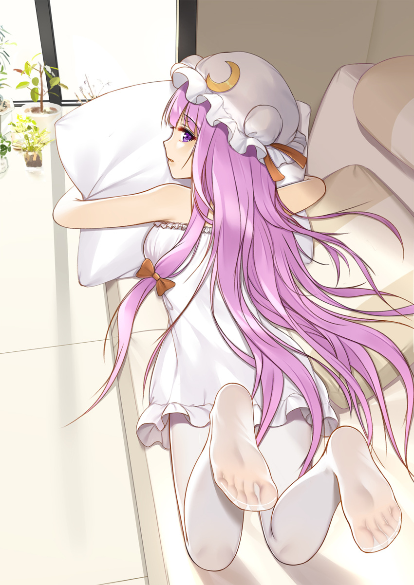1girl alternate_costume bare_arms bare_shoulders casual couch crescent crescent_hair_ornament dress feet feet_up flan_(seeyouflan) hair_ornament hat highres indoors long_hair lying mob_cap on_stomach pantyhose patchouli_knowledge pillow pillow_hug plant potted_plant purple_hair see-through soles solo strapless strapless_dress the_pose toes touhou very_long_hair violet_eyes white_dress white_legwear