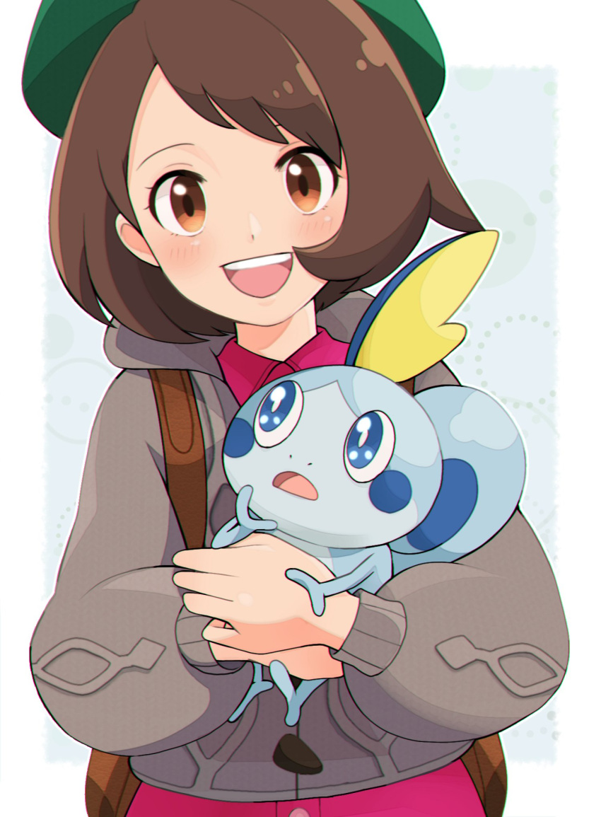 1girl :d backpack bag bangs blush bob_cut brown_bag brown_eyes brown_hair buttons cardigan collared_dress commentary dress gen_8_pokemon gloria_(pokemon) green_headwear grey_cardigan hat highres holding holding_pokemon hooded_cardigan looking_at_viewer nakikot_t open_mouth pink_dress pokemon pokemon_(creature) pokemon_(game) pokemon_swsh short_hair smile sobble starter_pokemon tam_o'_shanter teeth tongue