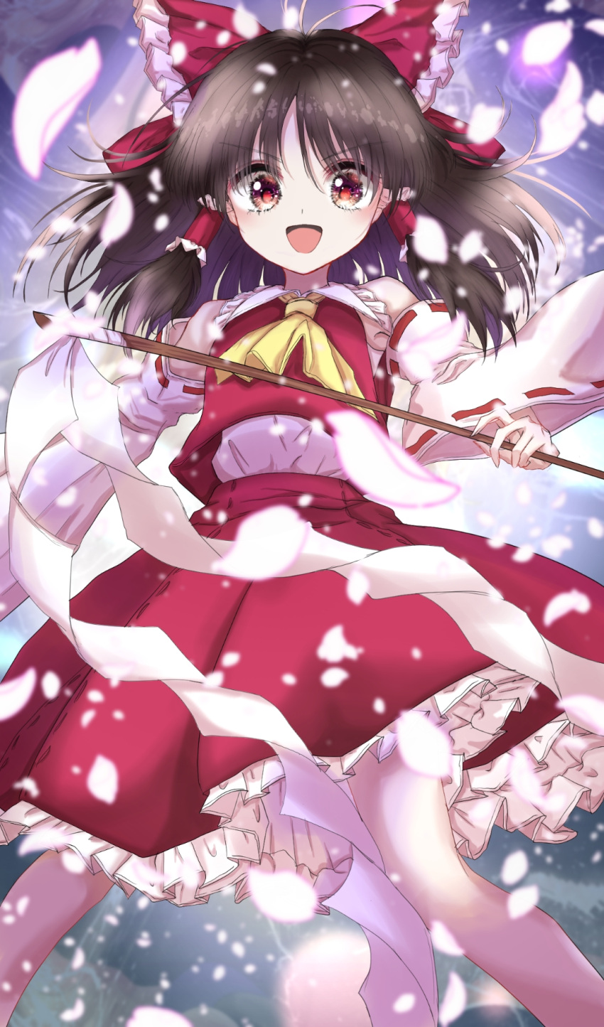1girl :d ascot bangs bare_shoulders blue_background blurry bow brown_eyes brown_hair commentary_request depth_of_field detached_sleeves eyebrows_visible_through_hair falling_petals feet_out_of_frame frilled_shirt_collar frills gohei hair_bow hair_tubes hakurei_reimu highres holding holding_stick kayon_(touzoku) legs_apart long_hair looking_at_viewer open_mouth petals petticoat red_bow red_pupils red_skirt red_vest ribbon-trimmed_sleeves ribbon_trim skirt skirt_set smile solo stick touhou v-shaped_eyebrows vest yellow_neckwear
