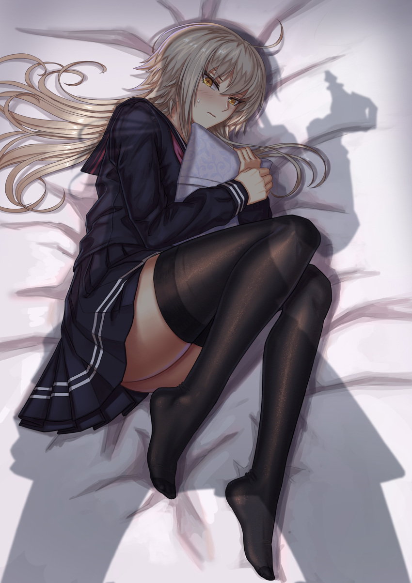 1girl ahoge bed black_legwear fate/grand_order fate_(series) feet highres jeanne_d'arc_(alter)_(fate) jeanne_d'arc_(fate)_(all) long_hair looking_at_viewer lying nairobi_song no_shoes on_bed pillow pillow_hug school_uniform serafuku shadow silver_hair skirt thigh-highs yellow_eyes