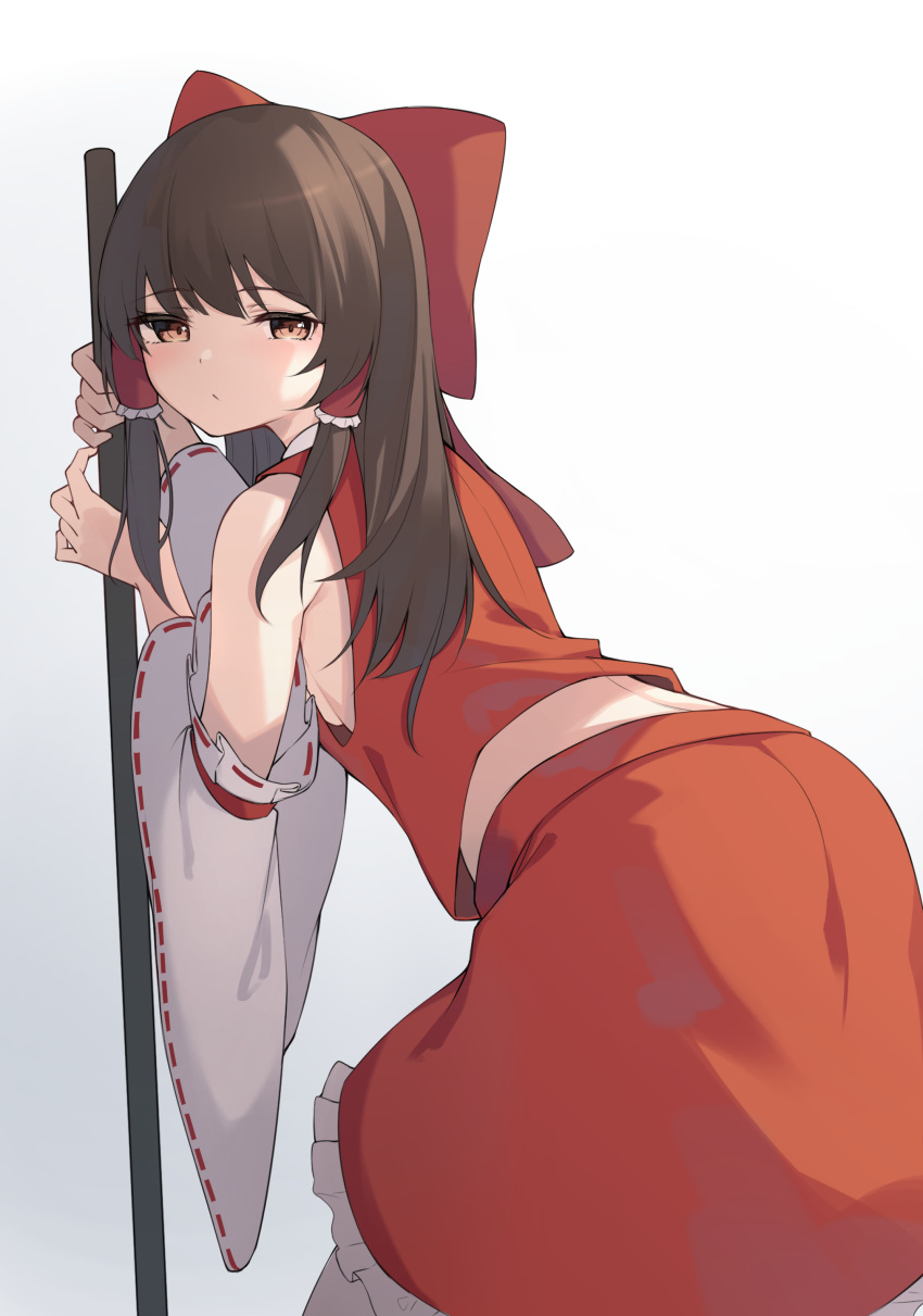 1girl absurdres bare_shoulders bow brown_hair detached_sleeves frilled_skirt frills from_behind hair_bow hair_tubes hakurei_reimu highres holding leaning_forward long_hair long_sleeves looking_at_viewer looking_back midriff red_shirt red_skirt shirt skirt skirt_set sleeveless sleeveless_shirt solo touhou wide_sleeves z_loader