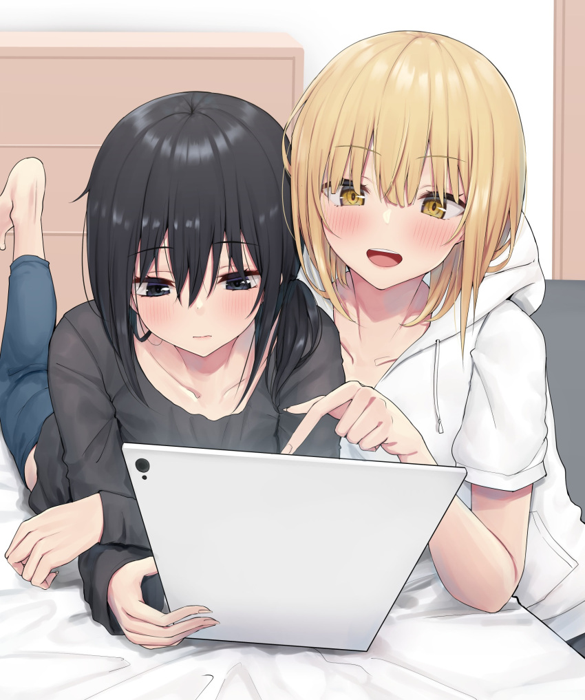 2girls barefoot bed black_hair black_shirt blonde_hair blue_eyes blush closed_mouth denim highres hood hoodie indoors jeans long_sleeves lying multiple_girls on_stomach open_mouth original pants piripun pointing shirt short_hair sitting smile tablet_pc white_hoodie yellow_eyes