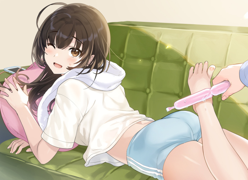 1girl ;d ahoge ass barefoot blue_shorts brown_eyes brown_hair couch holding leg_up long_hair looking_at_viewer lying midriff on_couch on_stomach one_eye_closed open_mouth original phone pillow shirt short_shorts short_sleeves shorts smile solo sweatdrop tan_(tangent) towel towel_around_neck tupet white_shirt