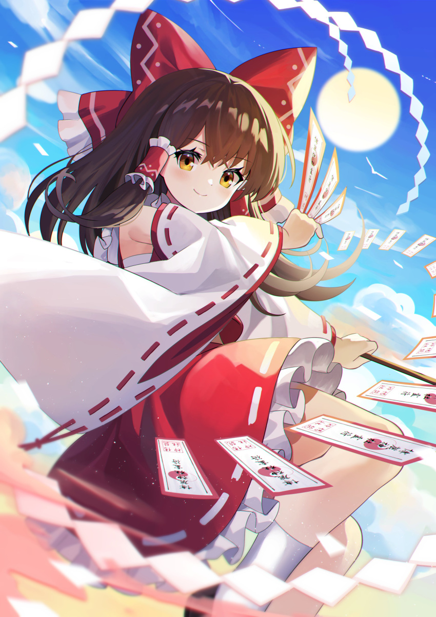 1girl absurdres between_fingers bow brown_eyes brown_hair day detached_sleeves feet_out_of_frame gohei hair_bow hair_tubes hakurei_reimu highres long_hair ofuda outdoors sarashi sky smile solo sun touhou yuujin_(yuzinn333)