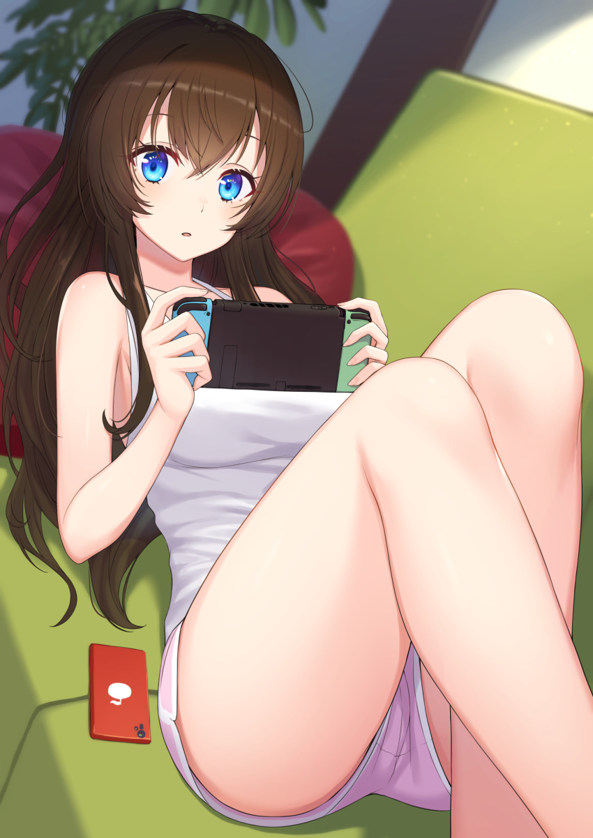 1girl bare_arms bare_legs bare_shoulders blue_eyes breasts brown_hair couch dolphin_shorts feet_out_of_frame game_console highres holding long_hair looking_at_viewer lying nintendo_switch nishino_eri on_back on_couch original parted_lips phone pink_shorts shirt short_shorts shorts sleeveless sleeveless_shirt solo thighs white_shirt