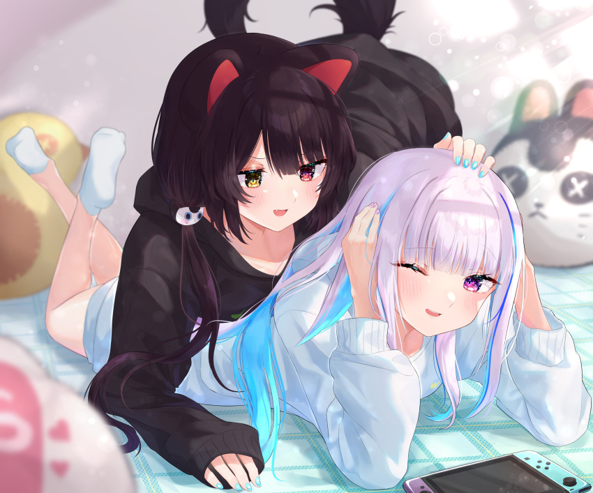 2girls ;) absurdres animal_ears bangs black_hair black_hoodie blue_hair blue_hoodie blue_nails blunt_bangs blurry blurry_background blurry_foreground blush commentary_request crossed_ankles dog_ears dog_girl dog_tail eyebrows_visible_through_hair fang hair_ornament hand_on_another's_head heterochromia highres hood hood_down hoodie inui_toko light_purple_hair lize_helesta long_hair long_sleeves looking_at_another lying multicolored_hair multiple_girls nail_polish nenehotoso nijisanji nintendo_switch no_shoes on_bed on_stomach one_eye_closed open_mouth purple_nails red_eyes sleeves_past_wrists smile socks streaked_hair stuffed_toy tail violet_eyes virtual_youtuber yellow_eyes