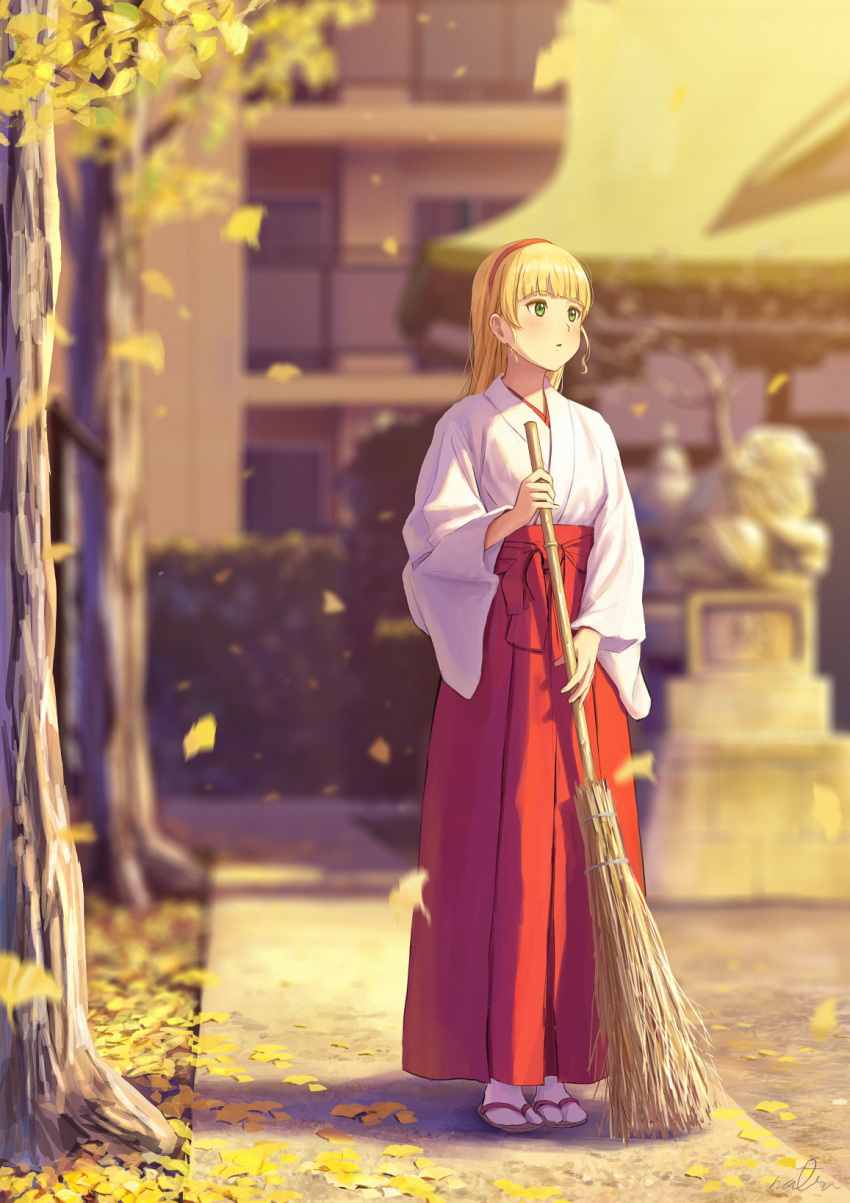 1girl autumn autumn_leaves bamboo_broom bangs blonde_hair blunt_bangs broom building full_body geta green_eyes hairband hakama heanna_sumire highres japanese_clothes leaf light_blush long_sleeves looking_away love_live! love_live!_superstar!! miko outdoors papi_(papiron100) parted_lips red_hakama solo sunset toeless_footwear torii tree white_legwear wide_sleeves