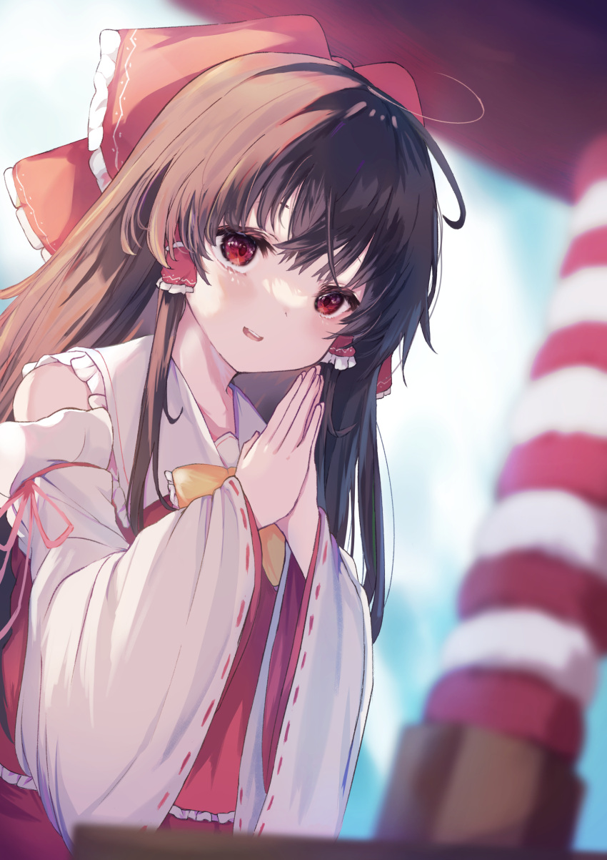 1girl :d absurdres alternate_neckwear bare_shoulders blurry bow bowtie brown_hair day depth_of_field detached_sleeves dutch_angle eyebrows_behind_hair hair_bow hair_tubes hakurei_reimu highres kogalashi long_hair outdoors own_hands_together red_eyes smile solo touhou wide_sleeves yellow_bow yellow_bowtie