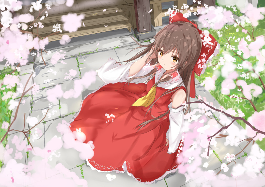 1girl absurdres ascot bangs blush bow branch brown_hair cherry_blossoms clip_studio_paint_(medium) closed_mouth day detached_sleeves eyebrows_visible_through_hair flower frills from_above grass hair_bow hair_tubes hakurei_reimu hand_in_hair hand_up highres long_hair looking_at_viewer na_kyo outdoors petals red_bow red_skirt shrine skirt solo spring_(season) standing touhou tree very_long_hair wide_sleeves yellow_ascot yellow_eyes