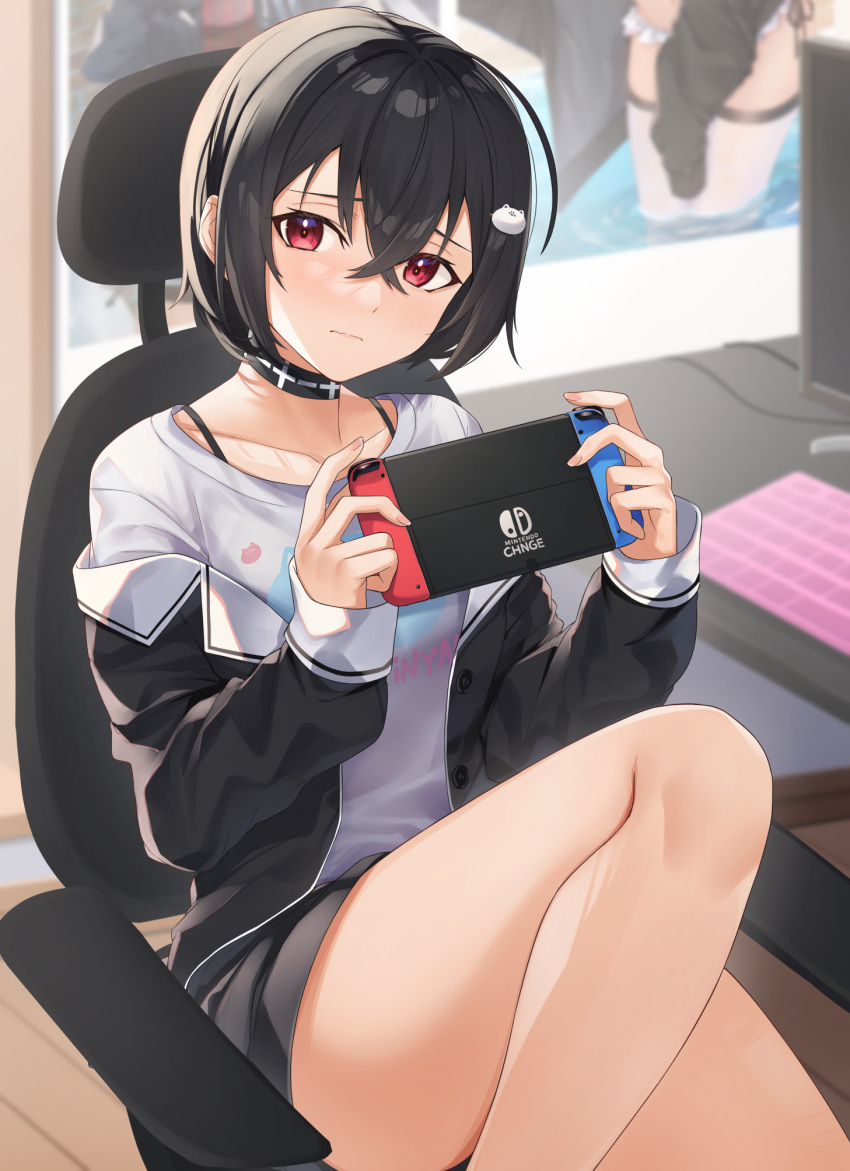 1girl bangs black_choker black_hair black_jacket black_shorts blush choker closed_mouth collarbone commentary_request crossed_bangs foot_out_of_frame hair_between_eyes hair_ornament highres holding indoors jacket keyboard_(computer) long_sleeves looking_at_viewer monitor nintendo_switch off_shoulder on_chair open_clothes open_jacket original poster_(object) red_eyes shirt short_hair shorts sitting solo table tapioka_(oekakitapioka) white_shirt wooden_floor