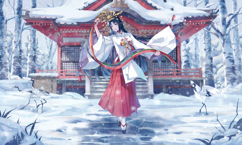 1girl bangs bell black_hair commentary commentary_request crown december hakama hakama_skirt highres hime_cut holding japanese_clothes jingle_bell kagura_suzu long_hair looking_at_viewer miko original personification red_hakama ryuu32 shrine skirt smile snow solo very_long_hair