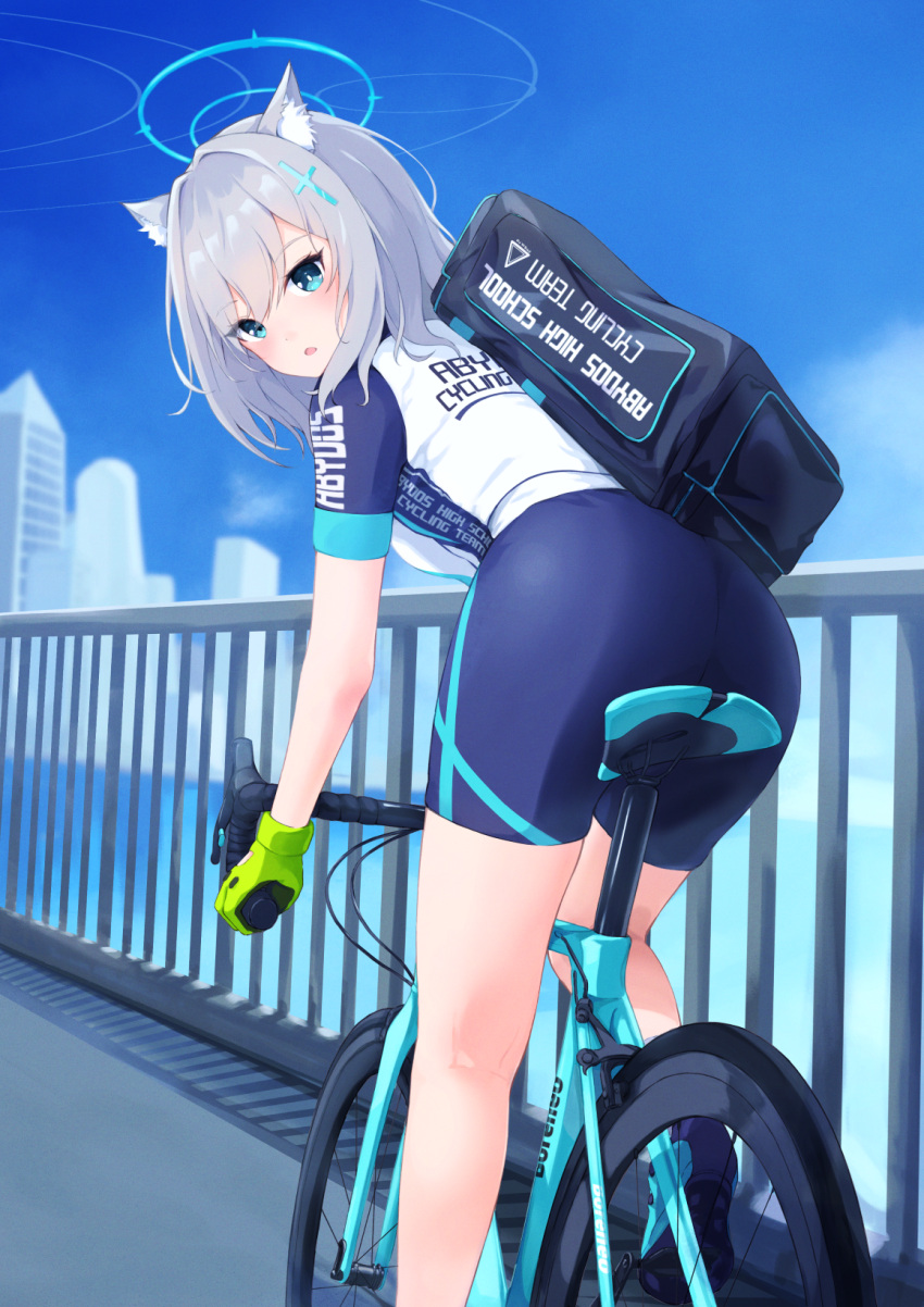 1girl animal_ear_fluff animal_ears aqua_eyes ass bag bangs bicycle bike_jersey bike_shorts blue_archive blue_shorts blurry blurry_background blush building cat_ears clothes_writing cross_hair_ornament duffel_bag evanstan gloves green_gloves grey_hair ground_vehicle hair_intakes hair_ornament halo highres looking_at_viewer looking_back medium_hair mismatched_pupils open_mouth outdoors riding_bicycle shiroko_(blue_archive) shiroko_(cycling)_(blue_archive) shoes short_sleeves shorts solo