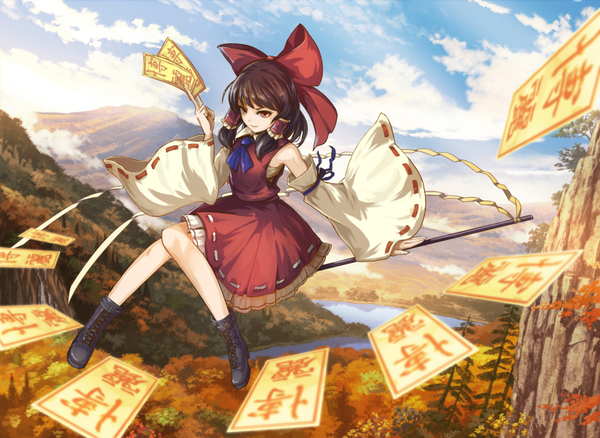 1girl ascot ashiya_azumi black_footwear blue_ascot blue_ribbon boots bow brown_hair cliff closed_mouth clouds commentary cross-laced_footwear day detached_sleeves forest frilled_hair_tubes frilled_skirt frills full_body gohei hair_bow hair_tubes hakurei_reimu holding knees_together_feet_apart long_sleeves looking_at_viewer medium_hair mountain nature orange_eyes outdoors red_bow red_skirt red_vest ribbon ribbon-trimmed_skirt ribbon-trimmed_sleeves ribbon_trim river sarashi sidelocks skirt skirt_set sky smile solo talisman touhou tree vest white_sleeves wide_sleeves