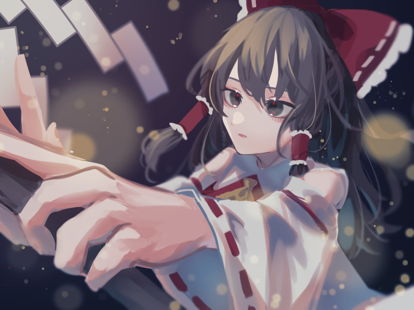 1girl ascot blurry bokeh bow brown_hair dark_background depth_of_field detached_sleeves foreshortening frills gohei hair_bow hair_tubes hakurei_reimu highres holding holding_stick japanese_clothes light_particles long_hair looking_ahead miko outstretched_arm parted_lips perspective red_bow red_eyes ribbon-trimmed_sleeves ribbon_trim roserose626 solo stick touhou upper_body wide_sleeves